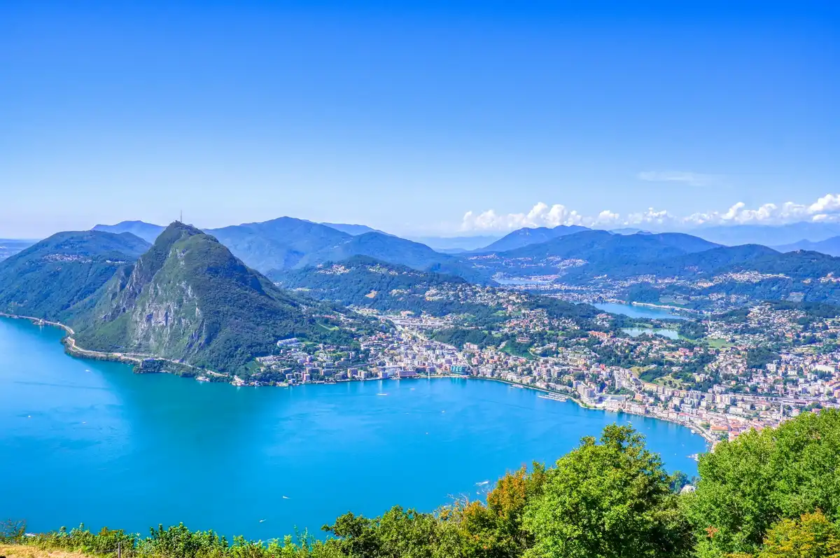 Green trees near body of water during daytime — Lugano, Switzerland