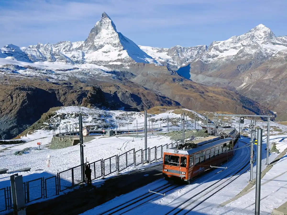 Red and black train on rail near snow covered mountain during daytime — Gornergrat, Switzerland