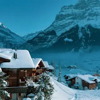 A snow covered mountain with a house in the foreground — Grindelwald, Switzerland
