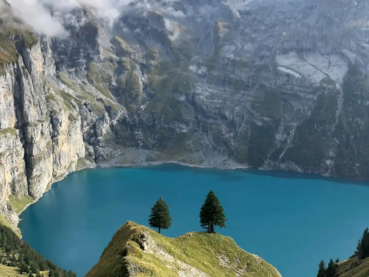 A blue lake surrounded by mountains and trees — Oeschinensee, Switzerland
