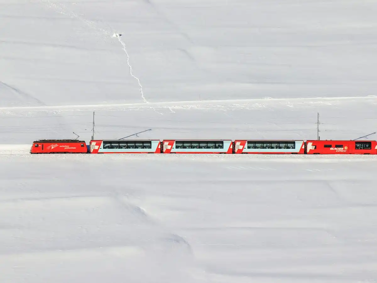 A red train traveling through a snow covered field — Glacier Express, Switzerland
