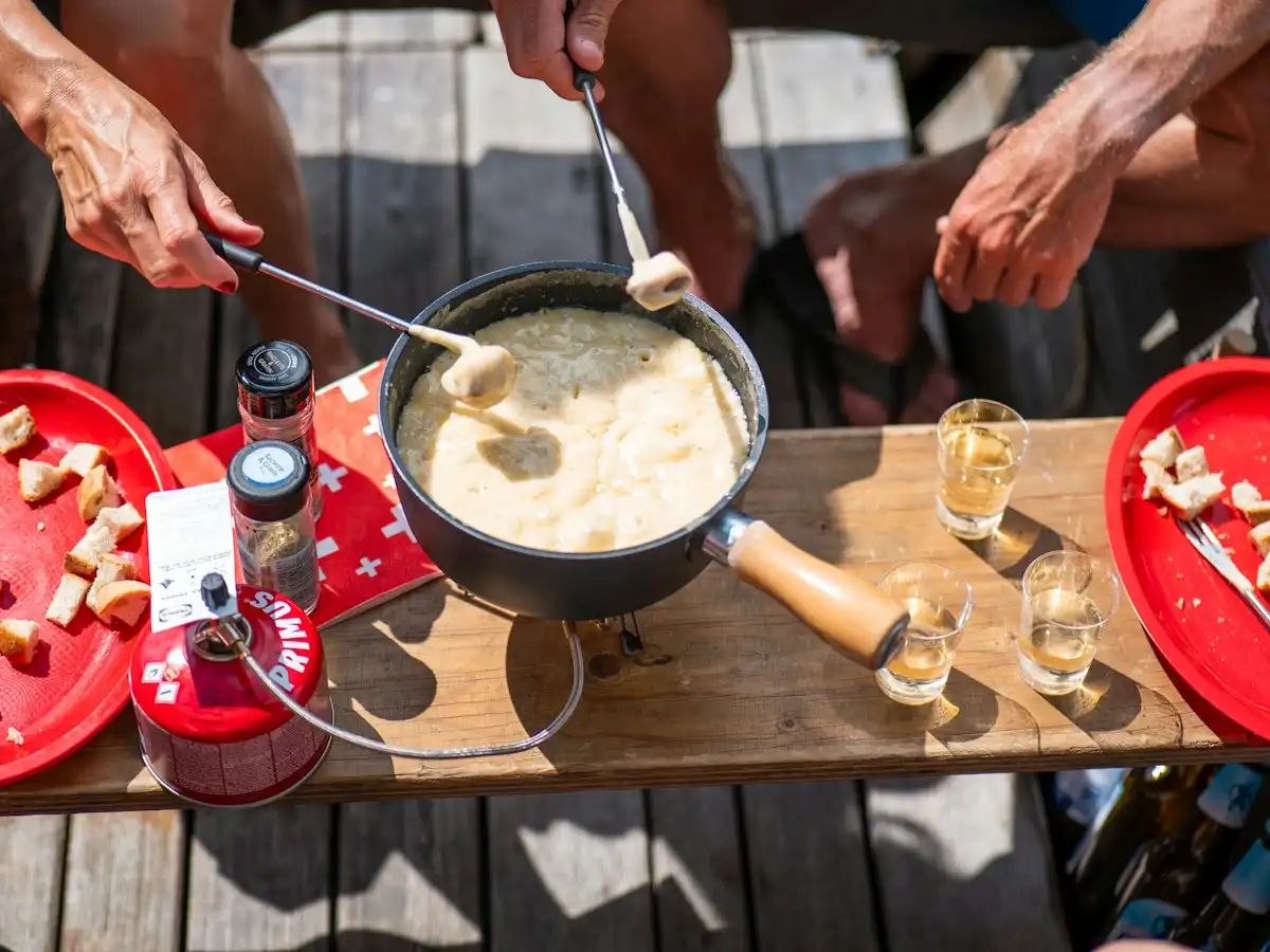 People dipping bread into a cheese fondue pot — Fondue, Switzerland