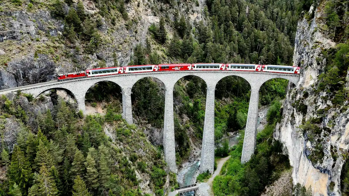 Red train crossing a tall viaduct in a forested valley — Landwasser Viaduct, Switzerland