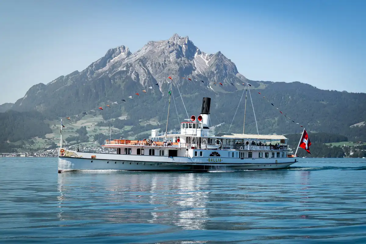 Historic paddle steamer cruising serene lake before a towering mountain — Lake Lucerne, Switzerland
