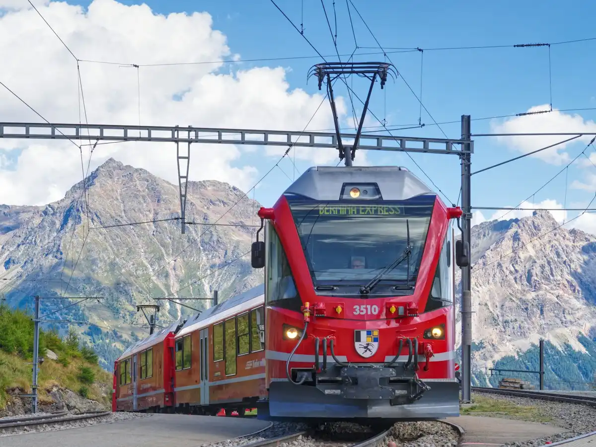 The red Bernina Express train traveling on tracks through a mountainous landscape — Alp Grüm, Bernina line, Switzerland